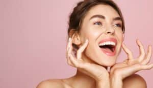 Beautiful woman smiles, cupping her face with her hands, following VirtueRF microneedling
