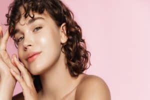 Woman smiles, touching her beautiful skin after microneedling with Tendu PN+HA