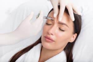 Patient during a neurotoxin treatment, closing her eyes as her provider treats frown lines